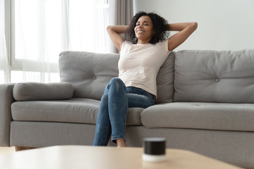Serene african woman leaned on couch resting in living room
