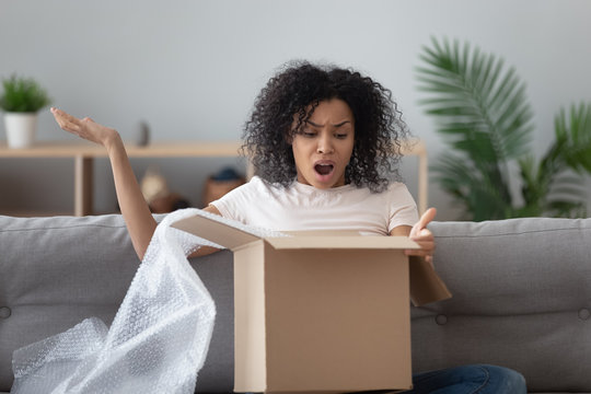 African woman unpack parcel feels angry see broken ordered goods
