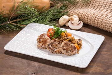 Pan roasted pork tenderloin medallions with mushroom and barley on wooden table