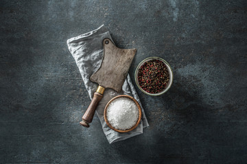 Old meat butcher on dark concrete board with spices salt and pepper