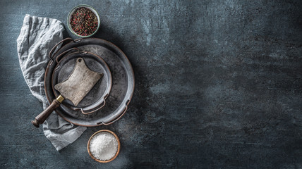 Old meat butcher on dark concrete board with spices salt and pepper