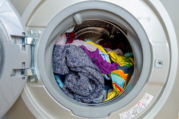 Washing machine with dryer, freshly washed clothes and dried in combined washing machine. Colored clothes, open doors, rubber seal, stainless drum, clean clothes