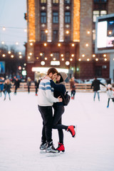 Young couple skates at the rink and embraces.