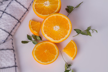 Orange fruits and green leaves on white background. Sweet orange fruit slices and kitchen towel.