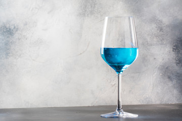 Exotic blue wine, trendy non-classical drink in wine glass on gray background