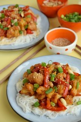 Cauliflower Kung Pao with bell pepper and rice noodles. Garnish with peanuts, scallions and sesame seeds. Vegan food