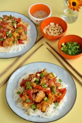 Cauliflower Kung Pao with bell pepper and rice noodles. Garnish with peanuts, scallions and sesame seeds. Vegan food