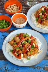 Cauliflower Kung Pao with bell pepper and rice noodles. Garnish with peanuts, scallions and sesame seeds. Vegan food