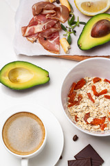 breakfast of oatmeal, milk, coffee, fried eggs and avocado on a white background