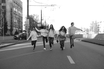 Multiracial group of friends runs and has a fun on city street.