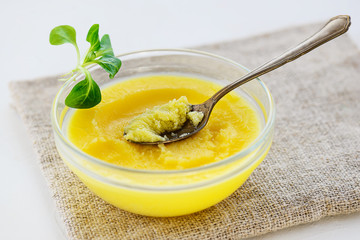 Ghee butter with greens in a bowl on a gray napkin.