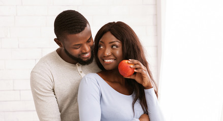 Happy black woman with apple looking at her husband