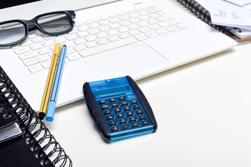Office desk in busy office with pens computer and note pads White modern desk with no people in shot