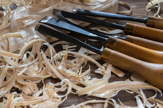 Instruments for wood carving with wood shavings at brown rustic old table. Wood craft background.
