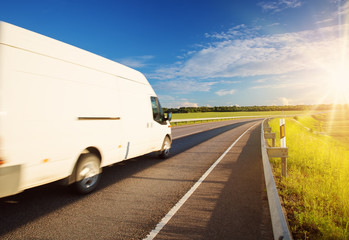 asphalt road on dandelion field with a small truck