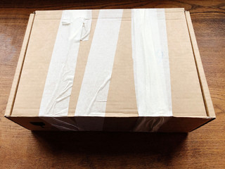 Closed cardboard box covered with duct tape on wooden table. Shipping equipment. Logistics 