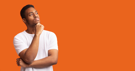 Pensive black man profile portrait on orange background