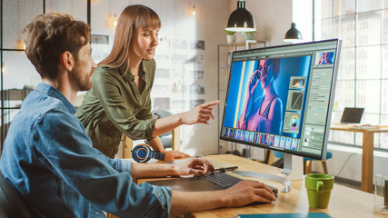Female Art Director Consults Designer Colleague, They Work on a Portrait in Photo Editing Software. They Work in a Cool Office Loft. They Look Very Creative and Cool. - obrazy, fototapety, plakaty