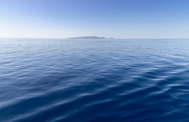 calm blue ocean with an island on the horizon