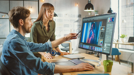 Female Art Director Consults Designer Colleague, They Work on a Portrait in Photo Editing Software. They Work in a Cool Office Loft. They Look Very Creative and Cool.