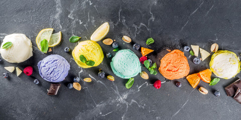 Colorful pastel ice cream with waffle cones and various flavor ingredients, black marble background, copy space top view
