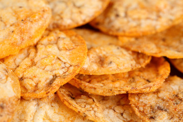 Extreme close up of a pile of organic, crispy, baked, whole grain rice chips with tomato and paprika spices. Gluten free healthy snack. Macro food background.
