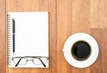 Obraz na płótnie Canvas Eyeglasse and notepad with coffee cup on wood deck