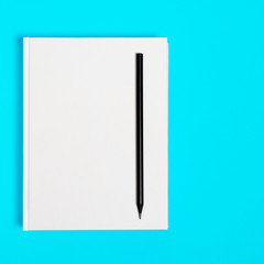 Mockup of closed blank square book and black pencil at colored textured paper background