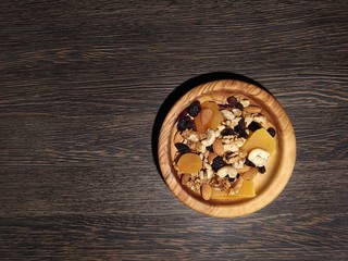 Snacks, all kinds of natural goodies on a dark background in a wooden plate
