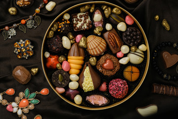 Handmade chocolate candies and sweets on background of jewelry and decorations.
