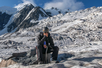 High altitude sickness. Climber breathing oxygen from the O2 tank on the background of glacier and...