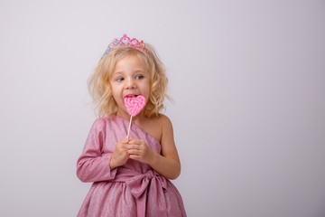 beautiful little blonde girl with a heart shaped Lollipop