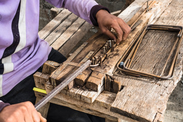 Close up of worker hand without wearing glove bending bending concrete reinforcing metal rods.