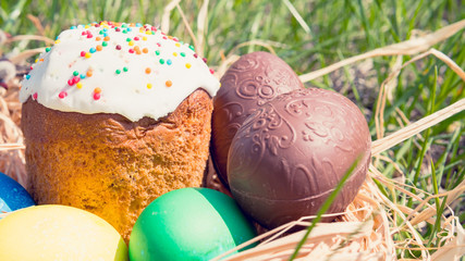 Close-up of sweet Easter cakes with colorful eggs among spring grass.