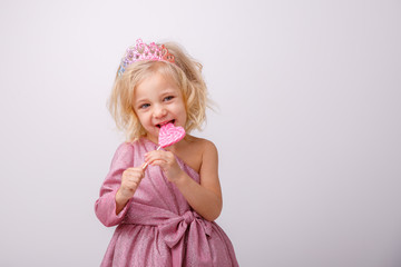 beautiful little blonde girl with a heart shaped Lollipop