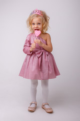 beautiful little blonde girl with a heart shaped Lollipop