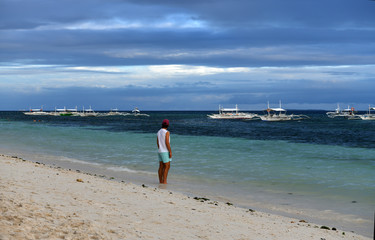 Obraz premium woman looks at the sea at sunset on a tropical island