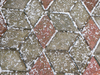 Snow on the paving slabs. Snow covered the tile. First snow
