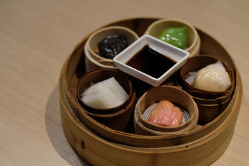 Close up colorful shrimp dumplings in steamer on wooden table. A traditional Cantonese dumpling served in dim sum. Blur background. 