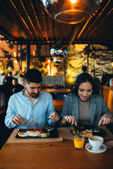 happy couple having breakfast in restaurant or food corner