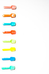 Colored Small plastic ice cream spoon are lined up on a white background, top view