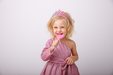 beautiful little blonde girl with a heart shaped Lollipop
