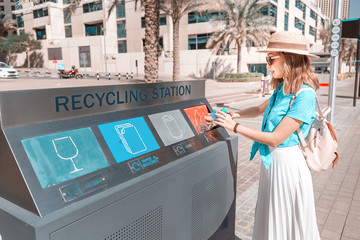 A girl sorts and throws garbage in a street station for recycling plastic waste. Environment...