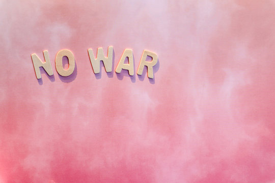 Wooden letters "NO WAR" on a pink background.