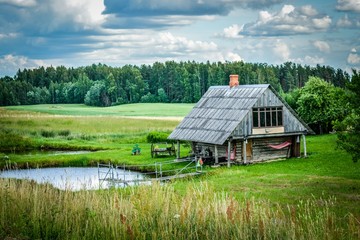 Small house near a pond in the countryside against a background of beautiful nature