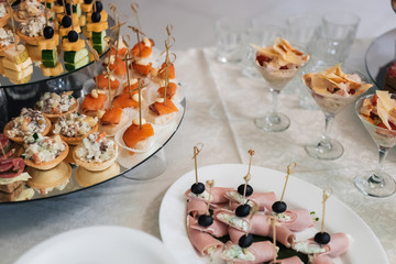 canapes with bacon, olives, cheese, cucumber and red fish on the festive table in the restaurant