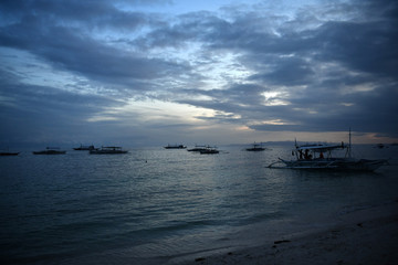 Fototapeta na wymiar fishing and tourist boats near the shore at sunset on a tropical island