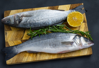 sea bass with rosemary and lemon on a wooden board