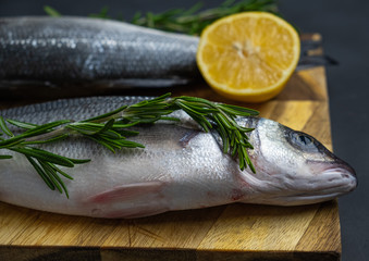 fresh sea bass with rosemary and lemon on a wooden board