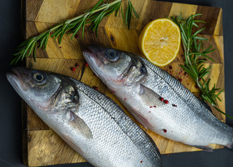fresh sea bass with lemon and rosemary on a wooden board